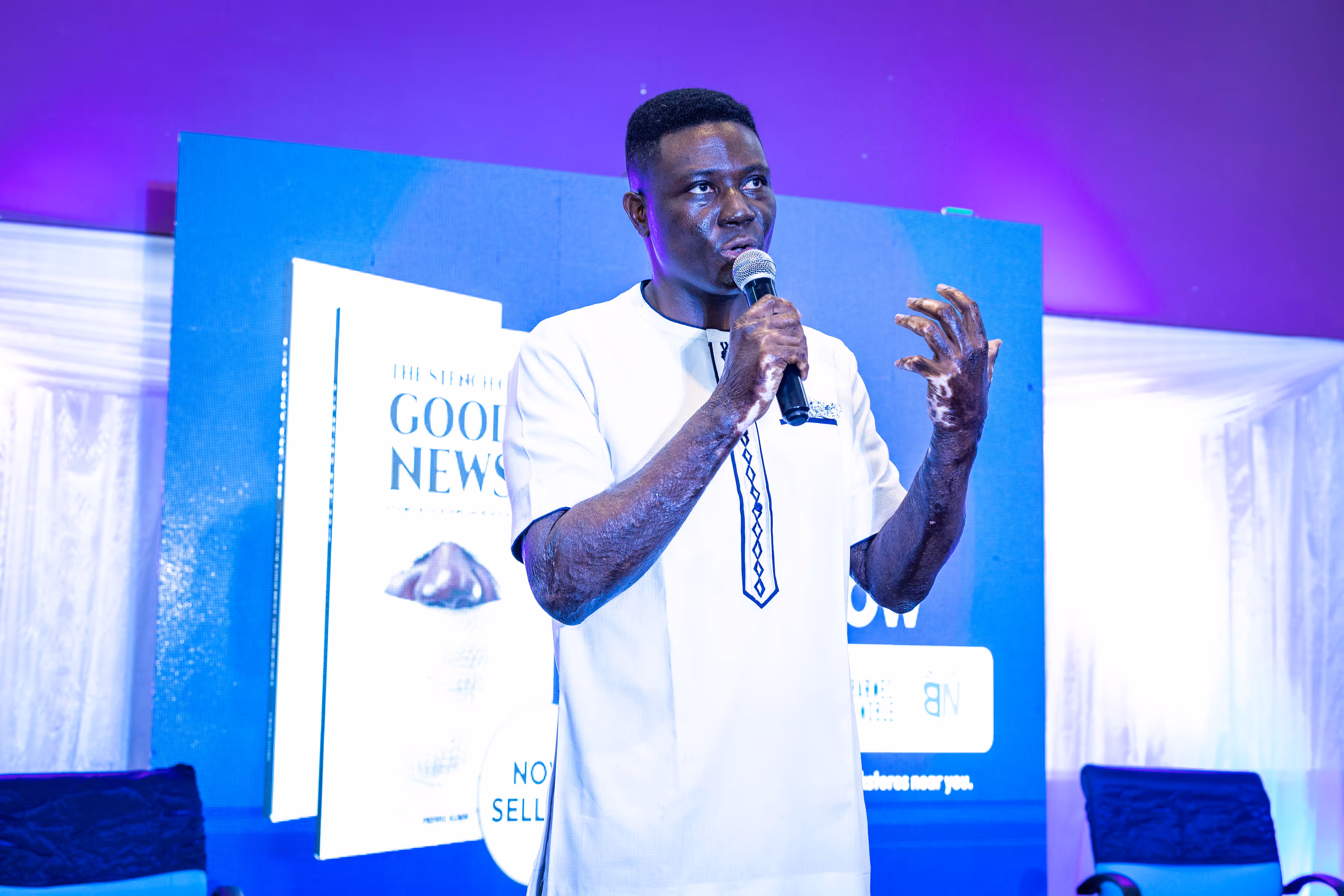 Dr Yaw Perbi is standing in front of a wall clock with Roman numerals endorsing Pierre's book