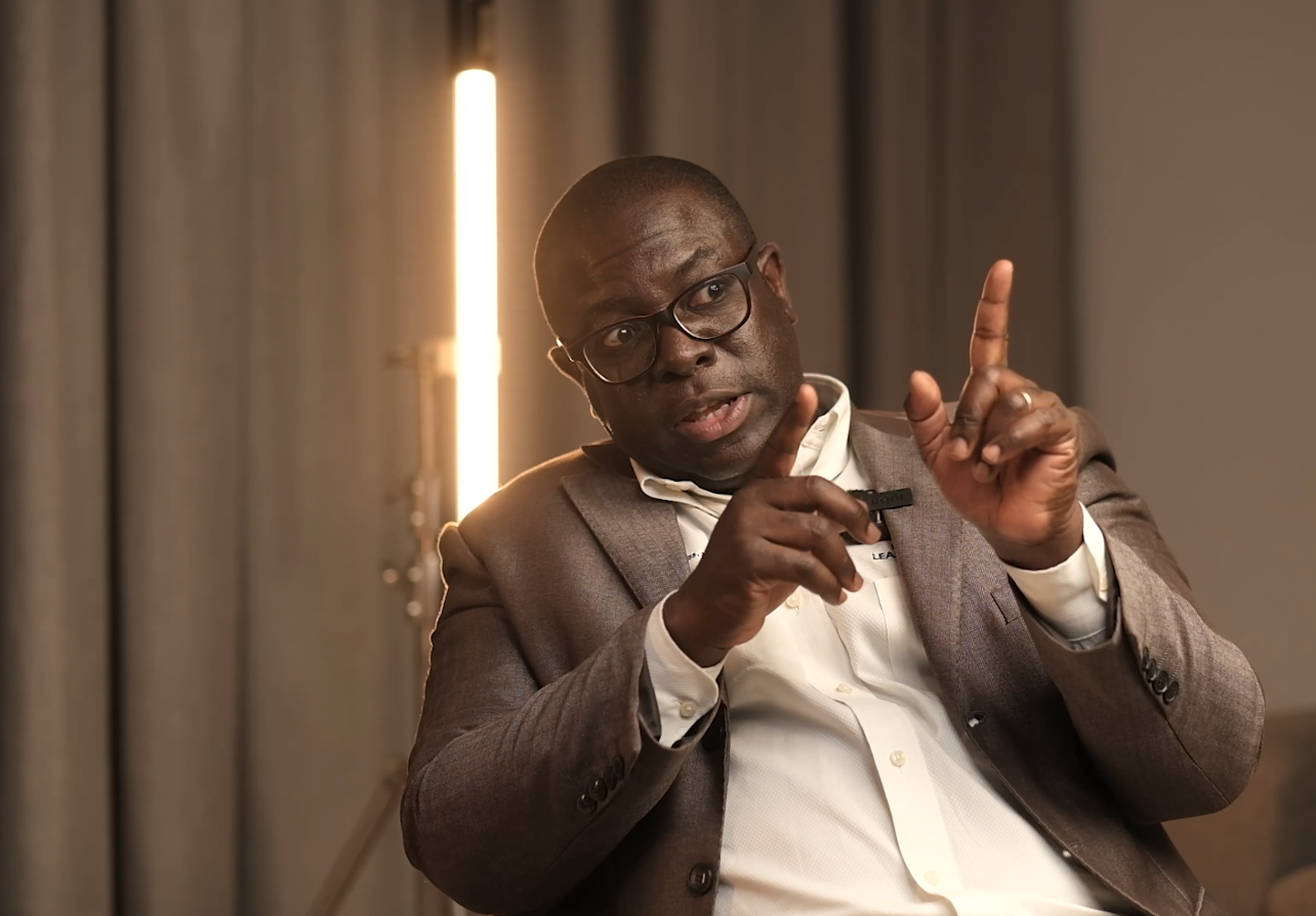 Dr Yaw Perbi is standing in front of a wall clock with Roman numerals endorsing Pierre's book
