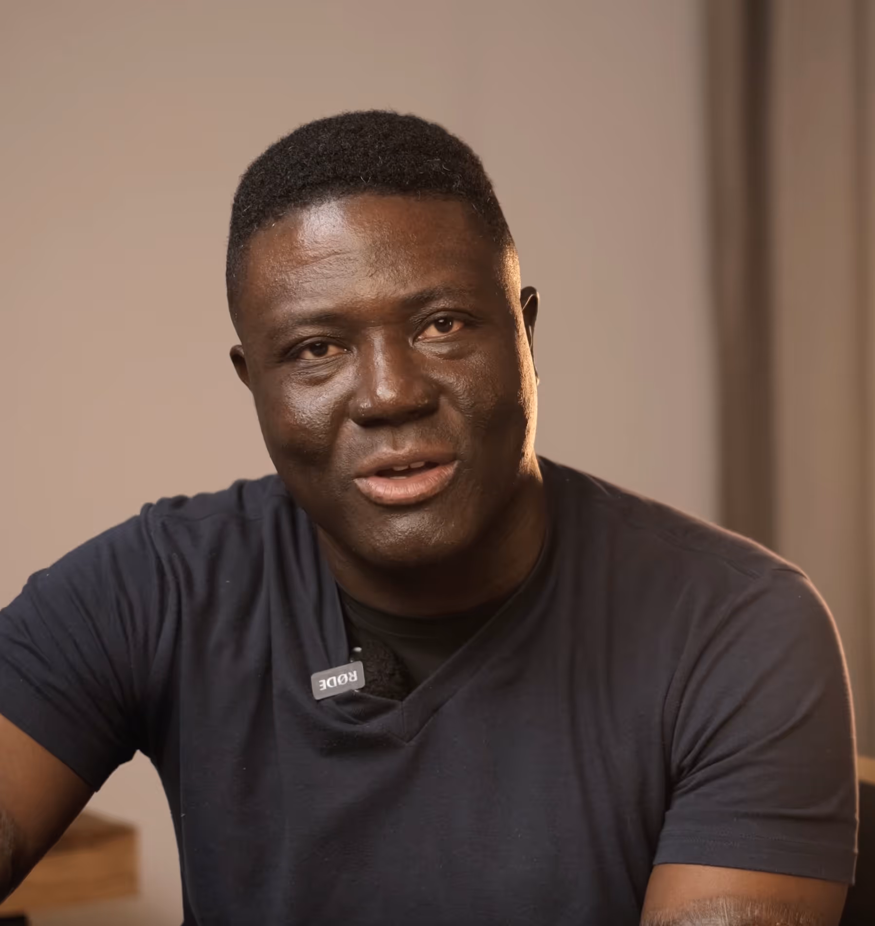 Dr Yaw Perbi is standing in front of a wall clock with Roman numerals endorsing Pierre's book